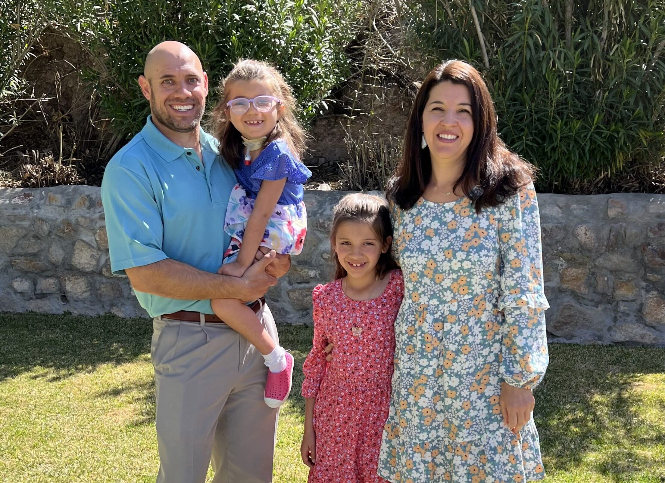 Family of four smiling with a girl affected by Leigh Syndrome