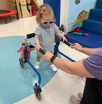 Little girl affected by Leigh syndrome using a gait trainer